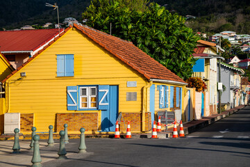 Fototapeta na wymiar Street view panorama of picturesque creole village “Les Anses-d'Arlet“ with colorful wooden houses and tropical vegetation. Idyllic popular holiday destination on caribbean island Martinique, France.