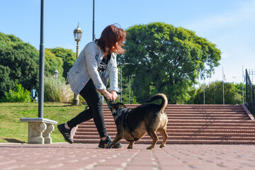 young latin woman playing with her pet in a park in Buenos Aires