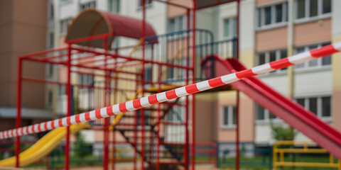 Fototapeta na wymiar Empty playground in courtyard fenced with red and white attention tape for children safety