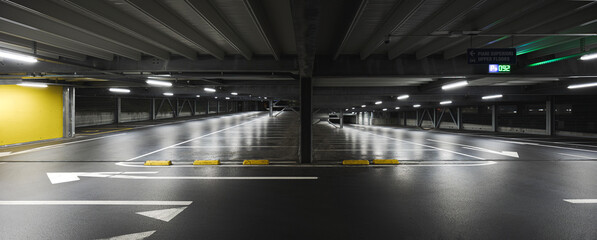 Modern underground garage with lamps illuminating the scene. Parking lines are drawn on the floor.