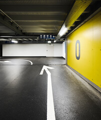 Modern underground parking garage with an arrow on the floor indicating the direction and a yellow...