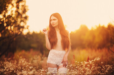 Beautiful sensual young Asian woman standing in the flowers field in sunset light, Beautiful brunette woman with long hair lingerie in a flowers field