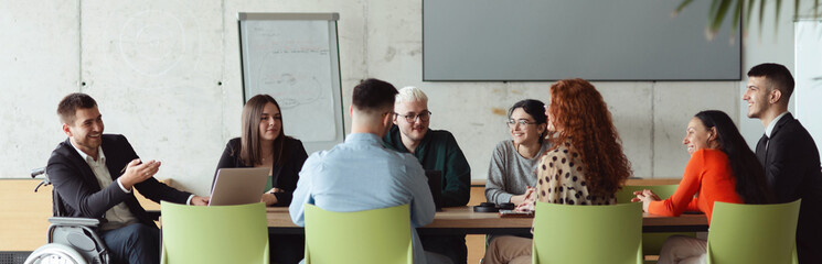 Wide crop photo of a diverse group of business professionals, including an person with a...