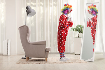 Full length shot of a clown getting ready in front of a mirror