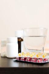 Attractive sick pregnant woman is lying in sofa. Taking pills from colds