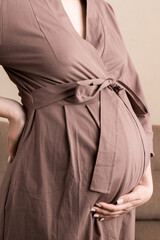 Pregnant woman hold back pain on sofa at thr home. Maternity healthcare concept support products