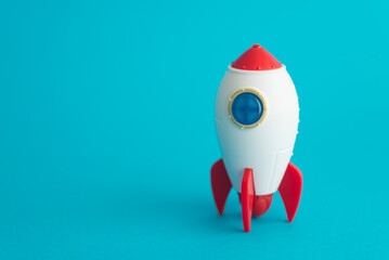 Cute rocket toy is launching on blue background copy space. Abstract business startup, innovation, development, business fast growth to successful goal target, space technology concept.