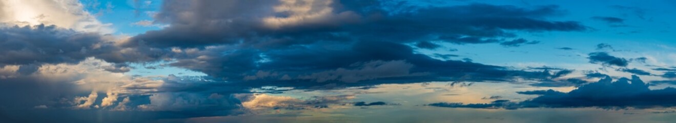 Fototapeta na wymiar Deep indigo storm clouds hang against the horizon in the rays of the setting sun.