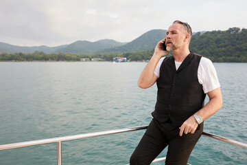 elderly man talking by smartphone in luxury yacht