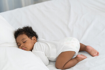 black african american baby sleeping on a white mattress.