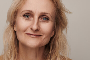 Beautiful blond middle aged woman smiling face looking camera portrait. Elegant mature lady no makeup 50 years old close-up isolated on white Women's health, cosmetology, skin care .