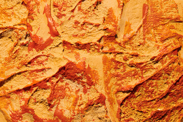 Decorative orange putty background. Wall texture with filler paste applied with spatula, chaotic dashes and strokes over plaster. Creative design, stone pattern, cement.