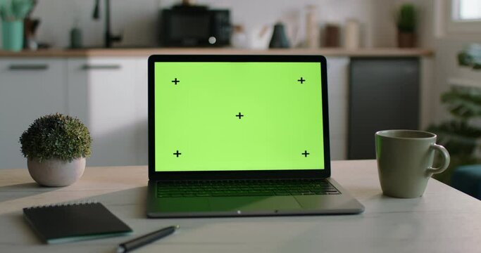 Template with laptop with green screen, chromakey. Perfect template for inserting your video, project, photo. Mockup with laptop on kitchen table. Green screen on display of modern portable laptop.