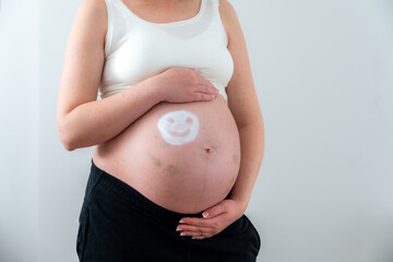 White emoticon on the girl's pregnant belly as a symbol of happiness