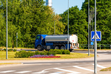 Tanker truck maneuvering in the narrow pass of a landscaped roundabout