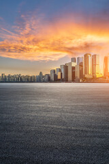 Asphalt road and city buildings at sunrise