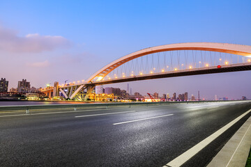 Asphalt road and bridge with city skyline in Shanghai at night, China.
