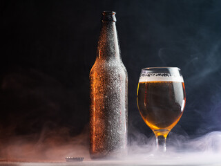 ice cold light beer in a glass. Bottle covered with ice. Dark background, copy space. smoke...