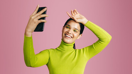 Taking glamour selfies in the studio, young generation z woman posing for a camera phone