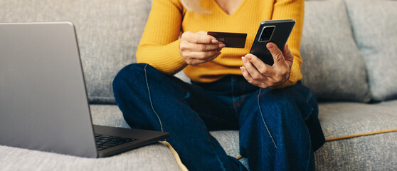 Mature woman using her smartphone for online shopping with credit card