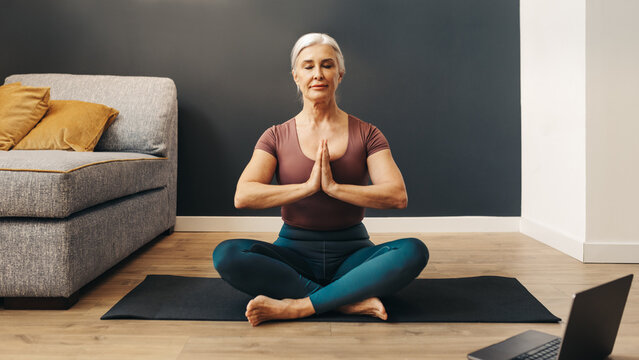Mindful woman practicing prayer pose during online yoga session