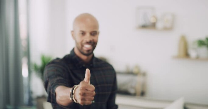 Happy man, hands and thumbs up for winning, achievement or success with positive attitude in living room at home. Portrait of excited male smiling showing thumb emoji, yes sign or like for approval