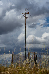 Pinwheel with the initials of the cardinal points on a cloudy day.