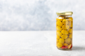 Olives in a glass jar on a concrete background. pitted green olives in jar.Pickled olives in glass...