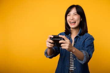 Portrait young asian woman with happy success smile wearing denim clothes holding joystick controller and playing video game. Fun and relax hobby entertainment lifestyle concept.