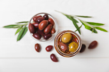Olives in a glass jar on a white wooden background. pitted green olives in jar.Pickled olives in glass jar. On a wooden background.Marinaded olives. Space for text.Space for copy. Vegan food.