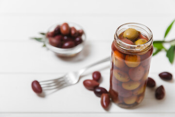 Olives in a glass jar on a white wooden background. pitted green olives in jar.Pickled olives in glass jar. On a wooden background.Marinaded olives. Space for text.Space for copy. Vegan food.