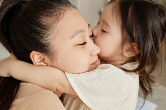 Asian little girl embracing and kissing her mom