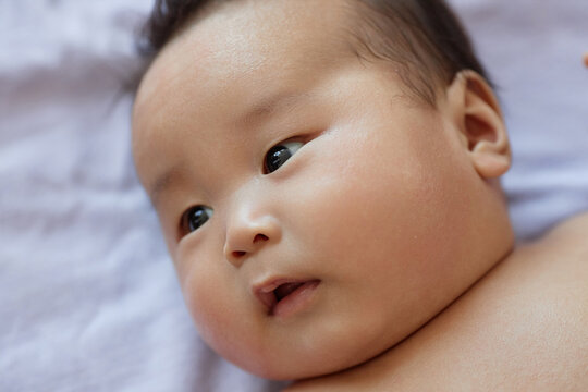 Close-up of Asian newborn baby lying in his cot