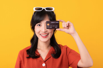 Portrait young beautiful asian woman happy smile dressed in orange clothes showing credit card...