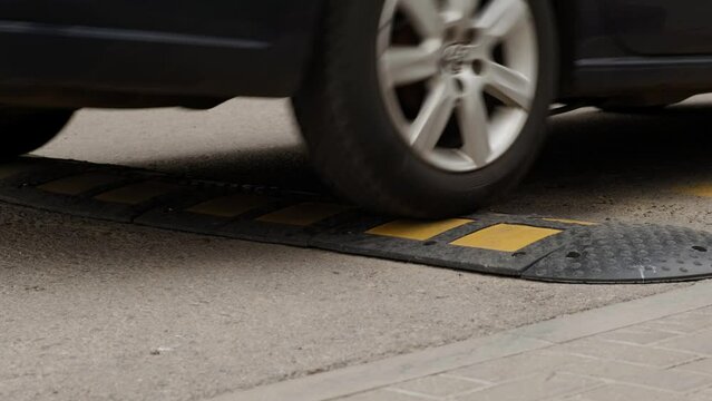 Blue Car Passes Speed Bumper on Street Road. Pedestrian Safety and Speed Control