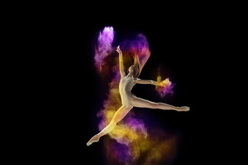 Artistic, talented young girl, ballet dancer in beige bodysuit performing with colorful explosion of powder over black studio background. Concept of art, festival, beauty of dance, inspiration, youth