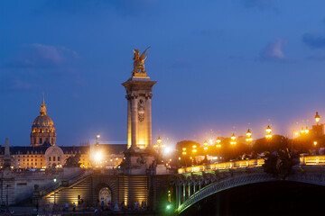 Obraz na płótnie Canvas Pont Alexandre III Bridge and illuminated lamp posts at sunset with view of the Invalides. 7th Arrondissement, Paris, France