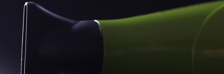 Green hair dryer with flat nozzle on dark background. Choosing a nozzle for hair styling blow dryer concept
