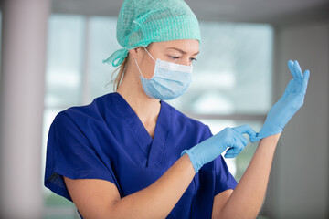 female nurse with a mask putting on gloves