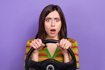Fototapeta na wymiar Portrait of astonished speechless girl dressed striped cardigan holding steering wheel staring at accident isolated on violet background