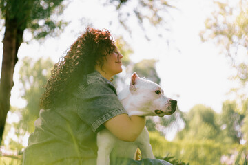 beautiful white dog of pitbull breed staffordshire terrier on a walk in the park with the owner on...