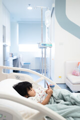 child is receiving medication through intravenous fluid therapy in hospital bed, focus on drip, and...