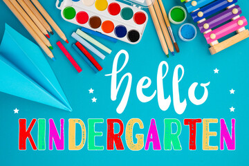 Hello kindergarten background. Top view flat lay concept. Childish lettering, colored paper, supplies, stationery for Pre-school, nursery school, kindergarten or preschool educational