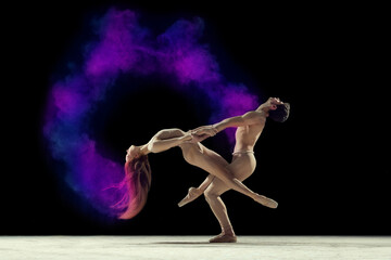 Expressive dance. Young man and woman, ballet dancers making performance with powder explosion against black studio background. Concept of art, festival, beauty of dance, inspiration, youth