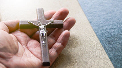 Holy wooden cross held on a hand with yellow texture in background                             