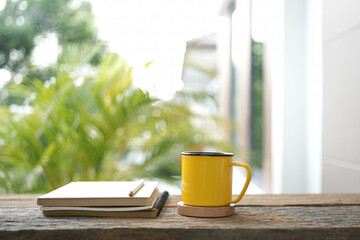 Yellow coffee cup and notebook on wooden tale
