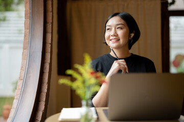 Freelance business woman sits in a good mood work at cafe. looking outside and thinking a new project plan. © Wasana