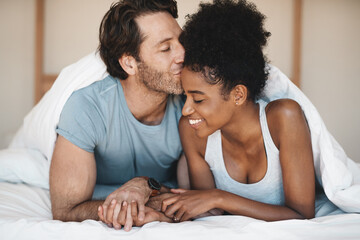 Happy interracial couple, bed and morning kiss in relax or bonding relationship at home. Man...