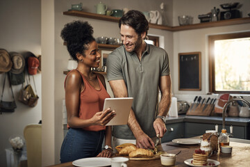 Interracial couple, tablet and cooking in kitchen for recipe, social media or online food vlog at home. Man and woman preparing breakfast meal or cutting ingredients together with technology on table