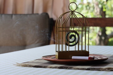 Metal mosquito coil holder and white lighter on a ceramic plate on the veranda